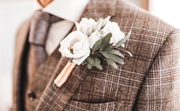 Homem de terno caro elegante personalizado com boutonniere posando o noivo colocou a gravata em linha reta vestindo no dia do casamento