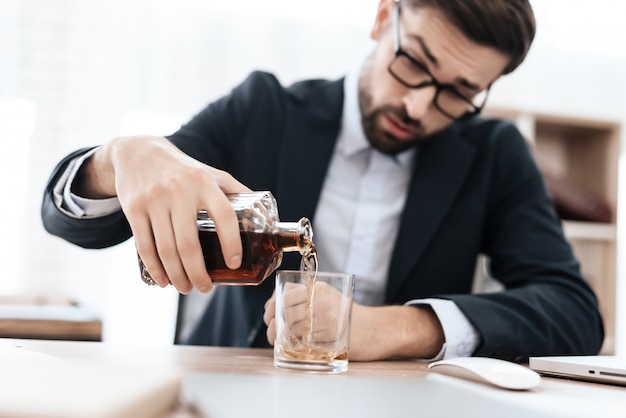 Homem de terno despeja-se álcool no escritório