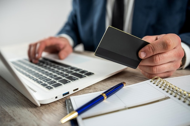 Homem de terno fazendo compras online e pagando com cartão de crédito usando laptop