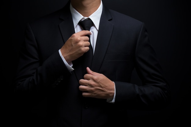 Foto homem de terno preto ajustando a gravata