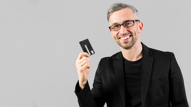 Foto homem de terno preto, segurando o cartão de crédito
