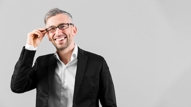 Foto homem de terno preto, usando óculos e sorrisos