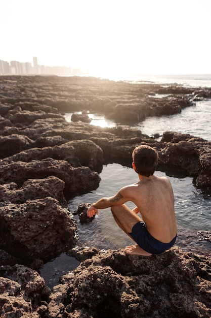 Foto homem de tiro completo com peito peludo à beira-mar