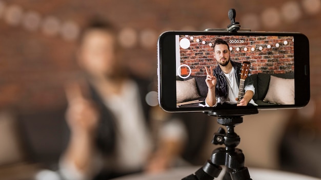 Foto homem de tiro médio gravando a si mesmo com o telefone