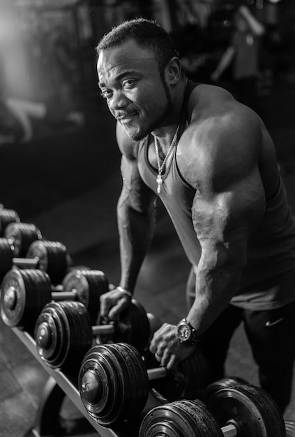 Foto homem de torso nu de atleta em frente a um espelho e se preparando para exercícios com halteres na academia conceito de saúde de estilo de vida foto em preto e branco