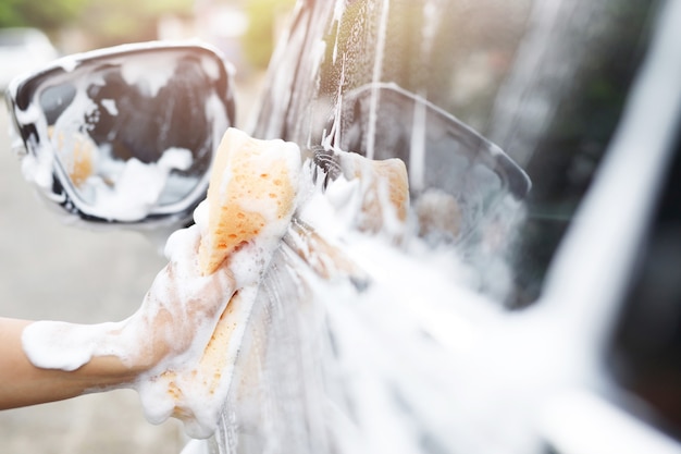 Homem de trabalhador de pessoas segurando a esponja amarela de mão e a janela do limpador de espuma de espuma para lavar o carro. lavagem de carros conceito limpa. deixe espaço para escrever mensagens.