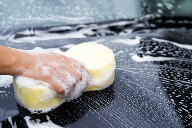 Homem de trabalhador de pessoas segurando a esponja amarela de mão e a janela do limpador de espuma de espuma para lavar o carro. Lavagem de carros conceito limpa. Deixe espaço para escrever mensagens.