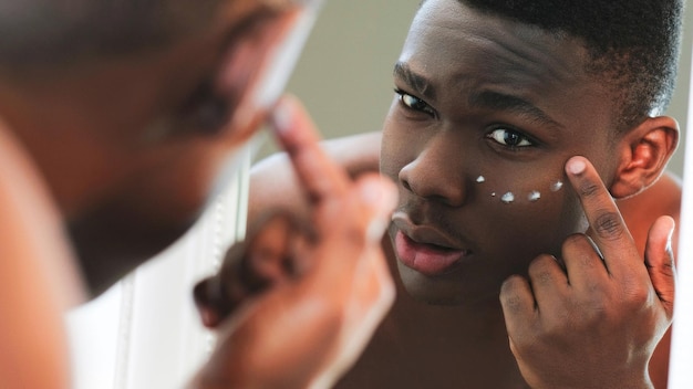 Homem de tratamento de pele creme facial aplicando sob o olho