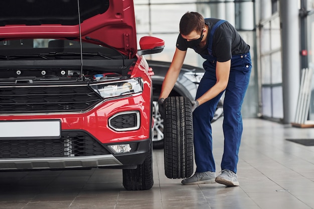 Foto homem de uniforme, trocar o pneu do automóvel. concepção de serviço automóvel