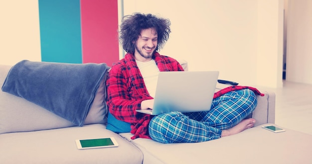 Homem de verdade usando laptop em casa tomando café desfrutando de relaxamento