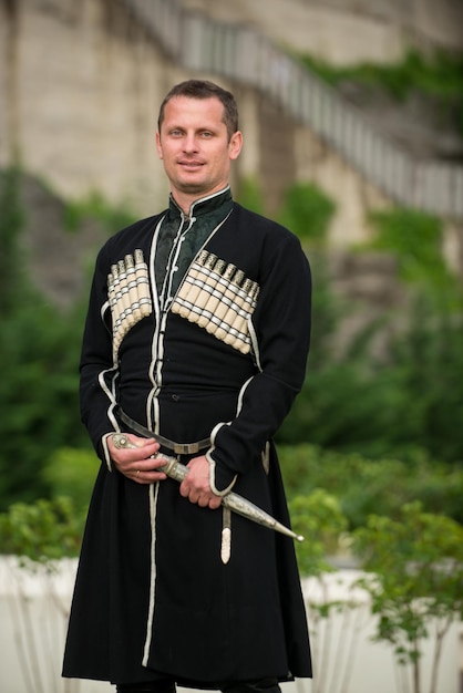 Foto homem de vestido nacional georgiano em um fundo de montanhas