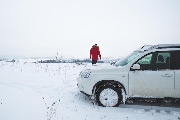 Homem de viagem de carro fora da estrada em pé e olhando para a bela vista de inverno