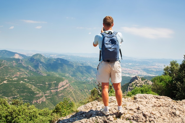 Homem de viagens com mochila em pé, tirar uma foto pelo smartphone mountians dia de sol cópia espaço