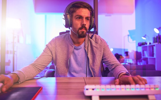 Foto homem de videogame de computador e fones de ouvido para jogos online de esports ou competição virtual em quarto escuro gamer guy jogos digitais e transmissão ao vivo no fone de ouvido em tecnologia de iluminação neon ou streamer de mídia