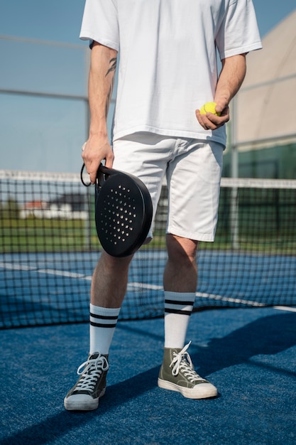 Homem de vista frontal segurando a raquete de tênis