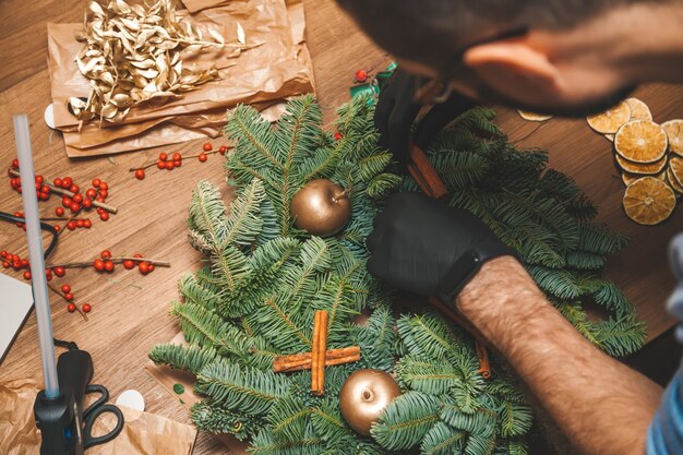 Homem decorando uma guirlanda de Natal Decoração de guirlanda de árvore de Natal com oficina manual faça você mesmo