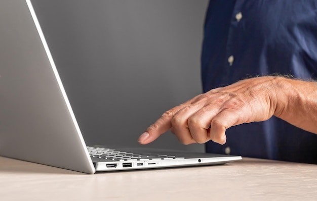 Homem dedo indicador pressionando o botão do teclado no laptop Macho usando computador para estudo de trabalho ou lazer enquanto está sentado na mesa