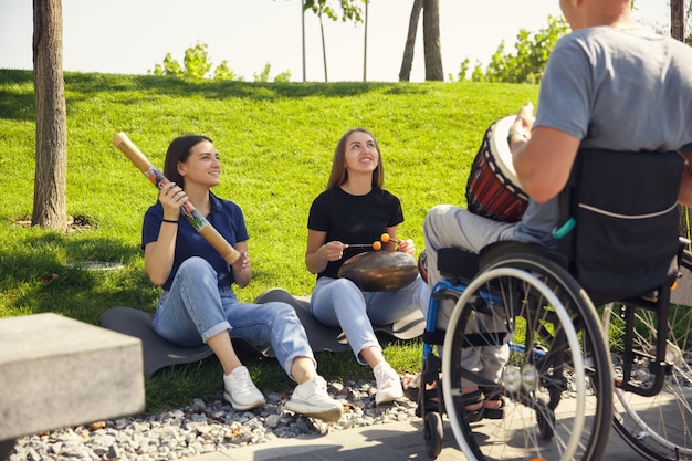 Homem deficiente feliz em uma cadeira de rodas passando um tempo com amigos tocando ao vivo