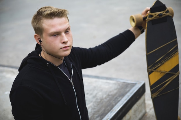 Homem deficiente jovem e motivado com um longboard no skatepark