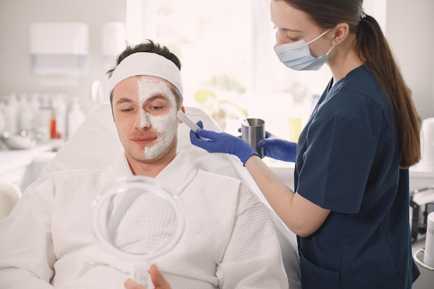 Homem deitado no armário de cosmetologista com uma máscara aplicada no rosto