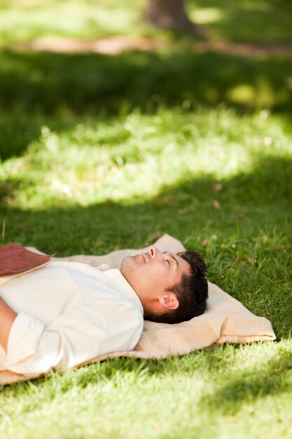 Homem deitado no parque com seu livro