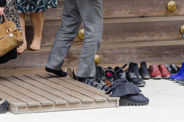 Homem deixando seus sapatos ao lado dos existentes na entrada do santuário ise jingu em ise japão