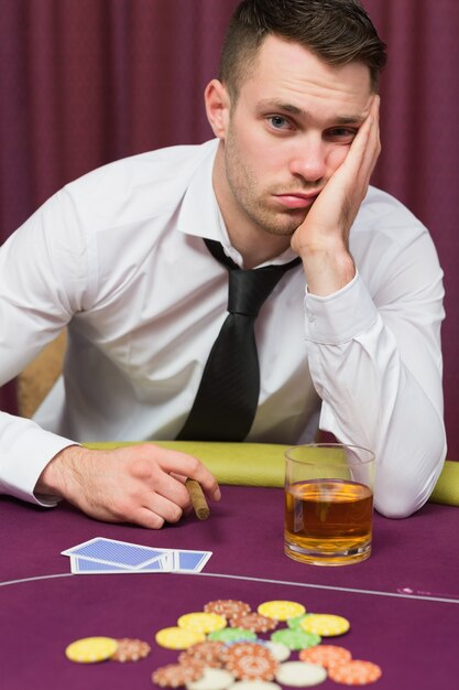 Foto homem deprimido na mesa de poker