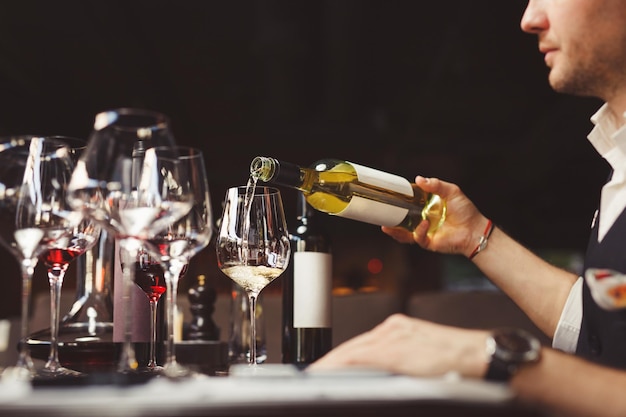 Homem derrama vinho branco em copo de vinho na mesa