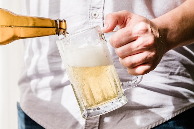 Foto homem derramando uma deliciosa cerveja fria em um copo durante um dia ensolarado