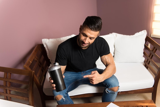 Homem descansando no vestiário com shaker