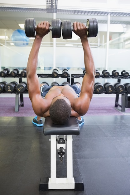 Foto homem descontraído que se exercita com halteres na academia