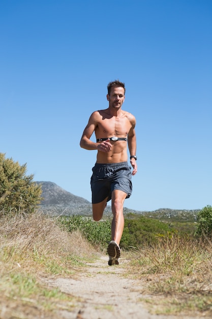 Homem descontrolado jogging com monitor de freqüência cardíaca em volta do peito