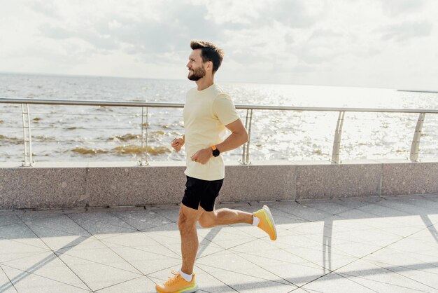 Foto homem desfrutando de uma corrida matinal à beira-mar em um dia ensolarado vestido com roupas esportivas e sapatos de corrida