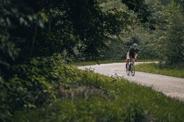 Homem desportivo com capacete e óculos a andar de bicicleta na natureza