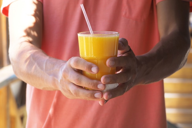 Homem detém copo com suco de manga natural fresco