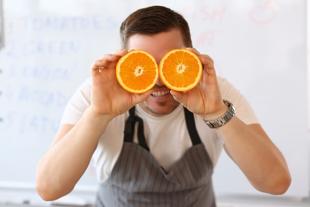 Homem detém metades de laranja cortada como olho