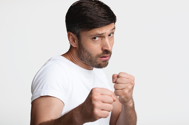 Homem determinado cerrando os punhos prontos para lutar sobre fundo branco