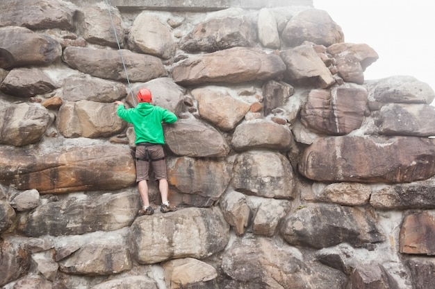 Homem determinado que escala um grande rosto de pedra