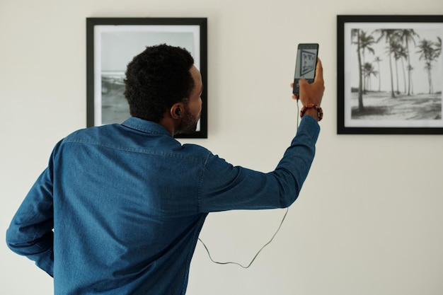 Homem digitalizando o código qr na fotografia na galeria de arte para ouvir audioguia