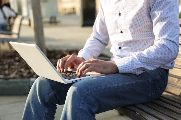 homem digitando no laptop ao ar livre close-up