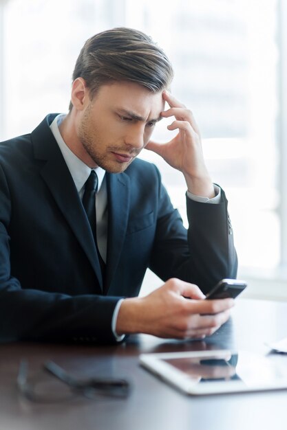 Foto homem digitando uma mensagem. jovem alegre usando telefone celular durante a pausa para o café no escritório