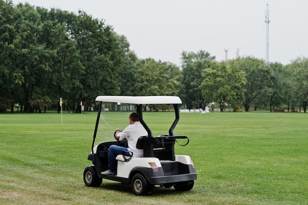 Foto homem dirigindo carro de golfe no campo de golfe