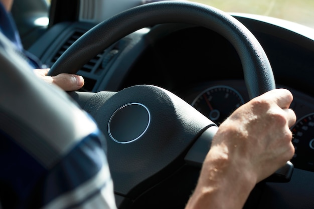 Homem dirigindo o carro, close-up. Mãos do motorista segurando o volante de um carro.