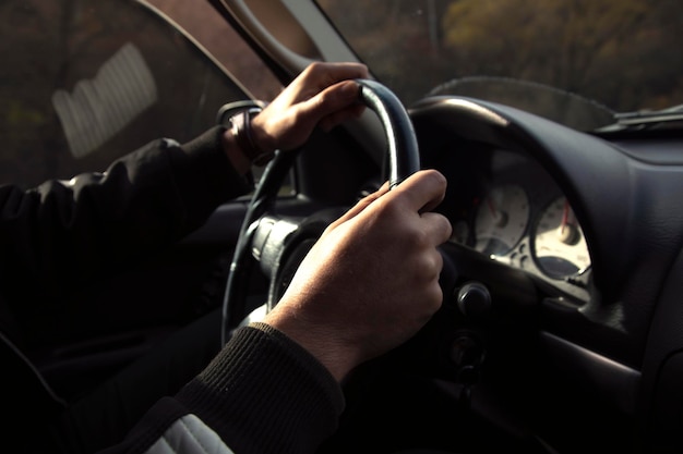 Homem dirigindo um carro com a mão no volante olhando para a estrada à frente