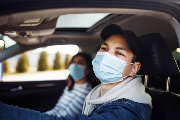 Homem dirigindo um carro com máscara médica esterilizada