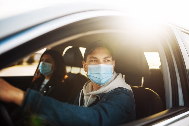 Homem dirigindo um carro com máscara médica esterilizada