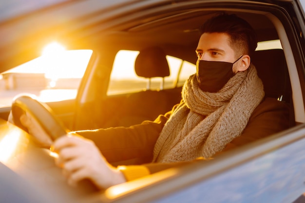 Homem dirigindo um carro usando uma máscara médica durante uma epidemia Isolamento de transporte Covid2019