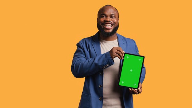 Homem divertido rindo enquanto apresenta um tablet com tela verde