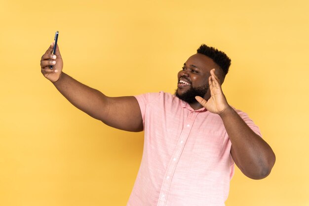 Homem dizendo oi fazendo videochamada usando smartphone sorrindo com sorriso aberto conexão 4g