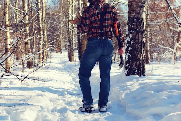 Homem do dia do sol com machado na floresta